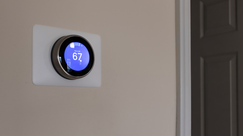 A smart thermostat on a wall next to a door
