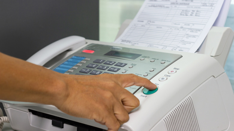 Hand pressing button on fax machine
