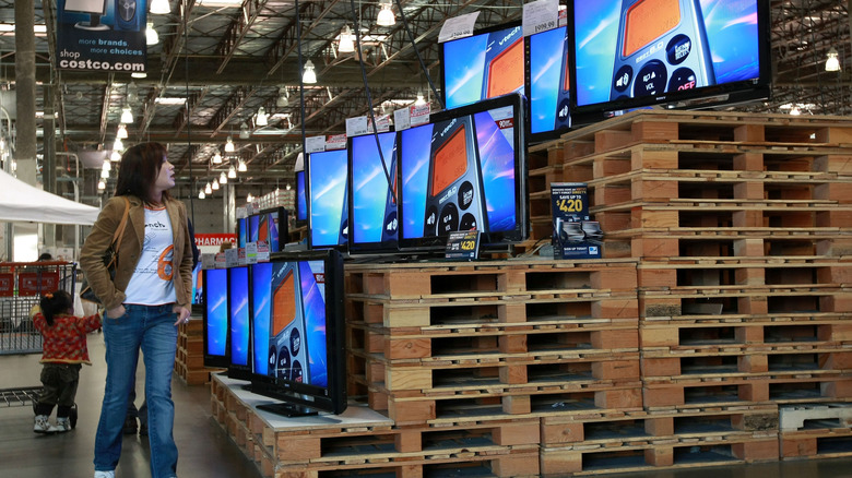 A customer walking by a display of TVs at Costco.