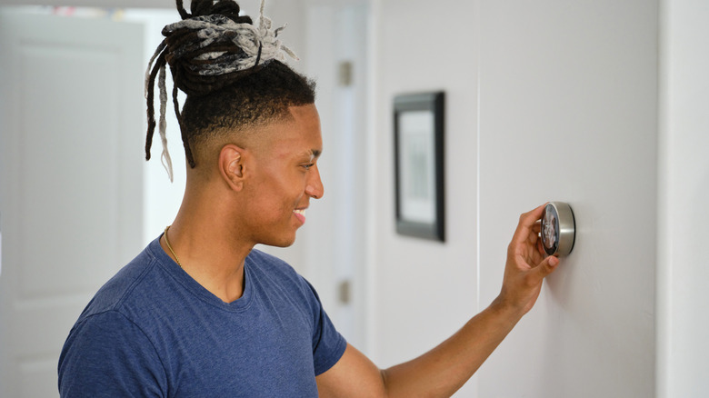 person adjusting their home smart thermostat