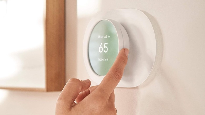 person adjusting a Google thermostat that supports Matter
