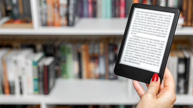 Someone holding and reading an e-book in a library setting.