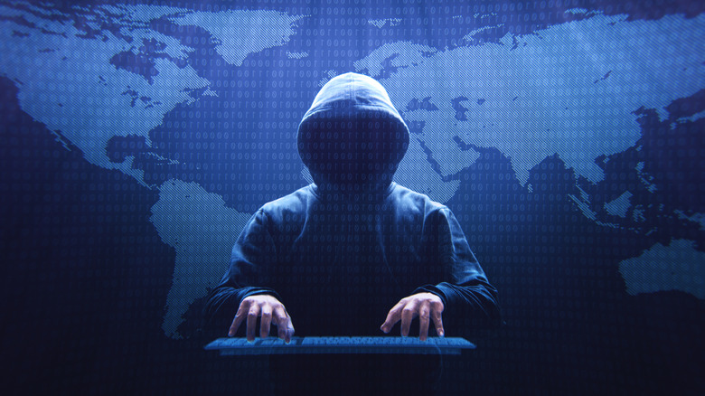 A generic, evil image of a silhouetted hacker against a dark backdrop of a world map.