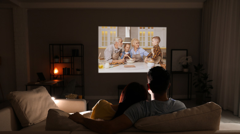 A couple using a projector to watch a movie at night