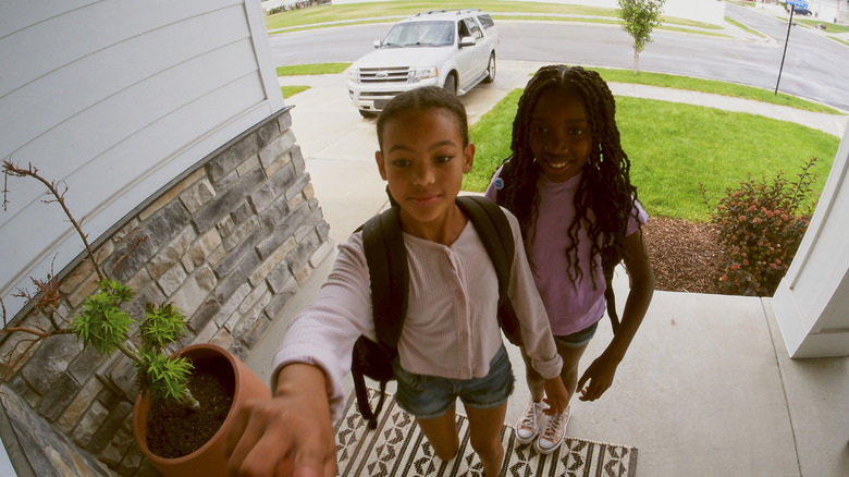 A video doorbell's view of two children in front of a door
