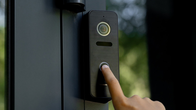 Close-up of a person pressing the button on a video doorbell