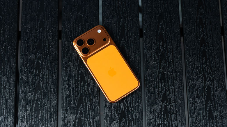 Apple iPhone 17 Pro in Cosmic Orange color on a dark wooden table