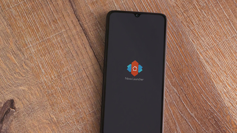smartphone on wooden floor shoving nova launcher icon on black screen