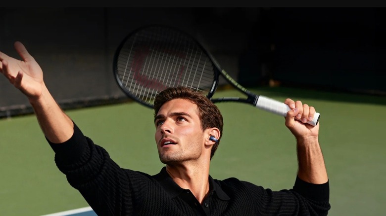 Person playing tennis while wearing clip-on earbuds