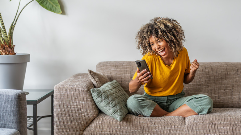 Happy woman on couch holding non-Apple phone