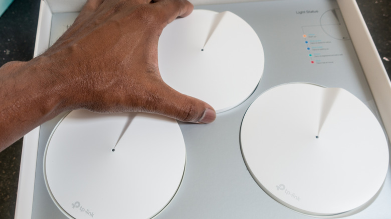 A person unboxing a whole home Wi-Fi mesh system from TP-Link