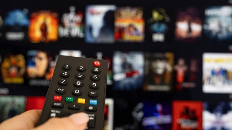 Close-up of person using remote to choose movies to download from TV