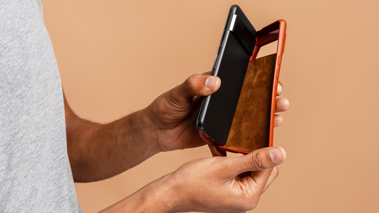Two hands removing phone case from smartphone