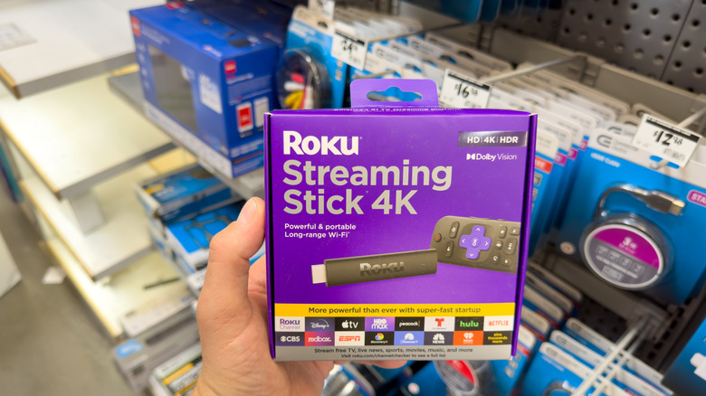 A person holding a Roku streaming stick 4K box inside a store