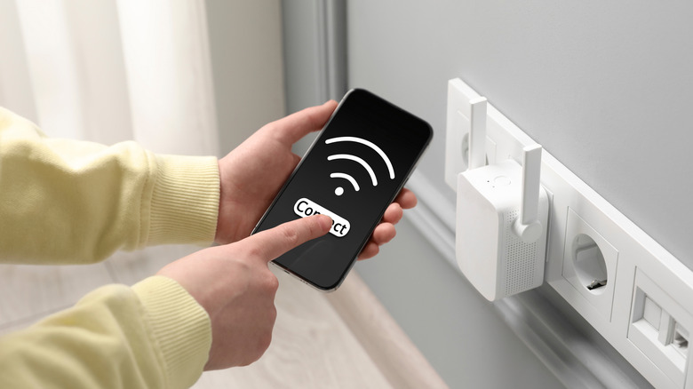 A person connecting to Wi-Fi on a smartphone via a Wi-Fi extender
