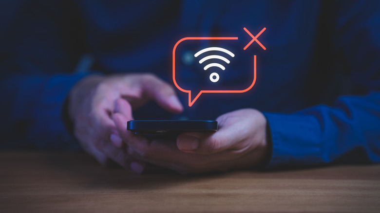 Close-up of a hand holding a smartphone with a graphic indicating poor a Wi-Fi connection