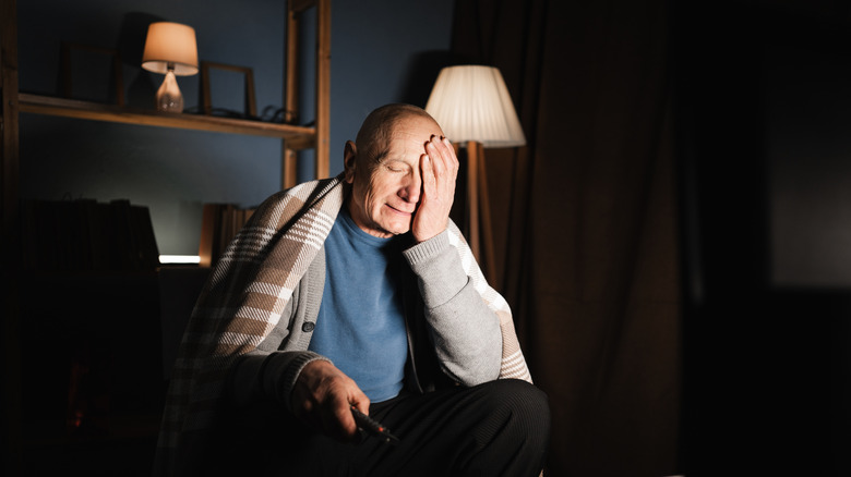 An older person expressing frustration with a TV