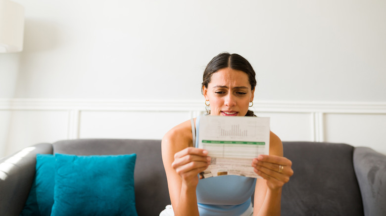 A young person reviewing a bill and looking stressed