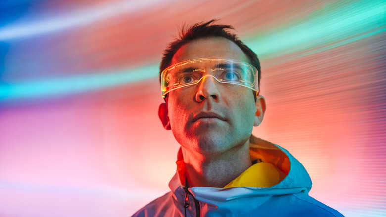 Man wearing futuristic glasses with neon lights in the background.