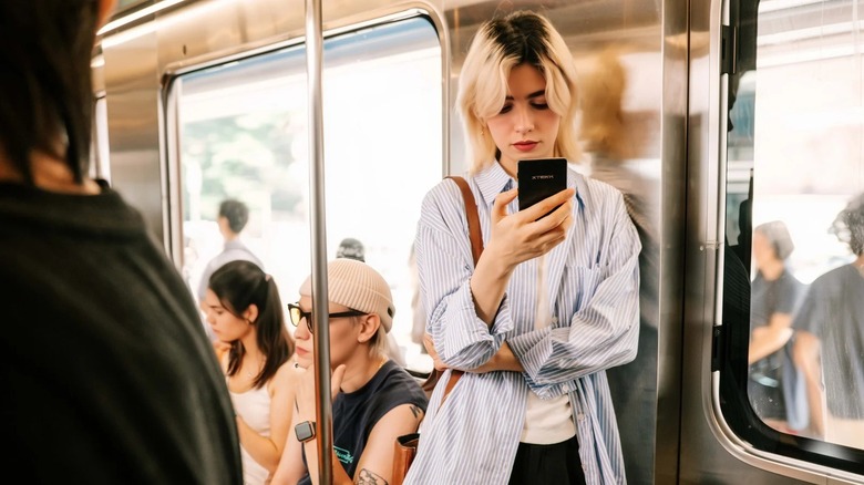 Woman reading on smartphone-sized e-reader in public transportation