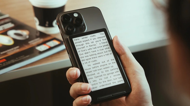 Xteink X4 attached to back of iPhone with book open