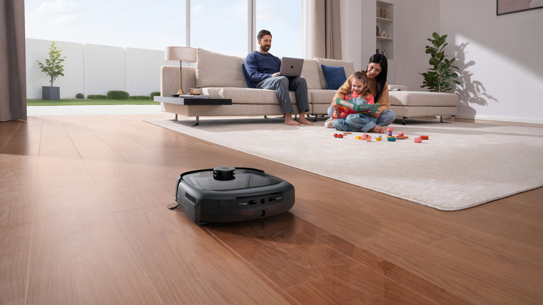 Eufy vacuum robot cleaning as parents play with child and work in background