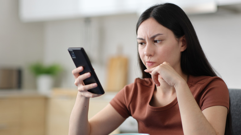 Woman looking suspiciously at smartphone screen