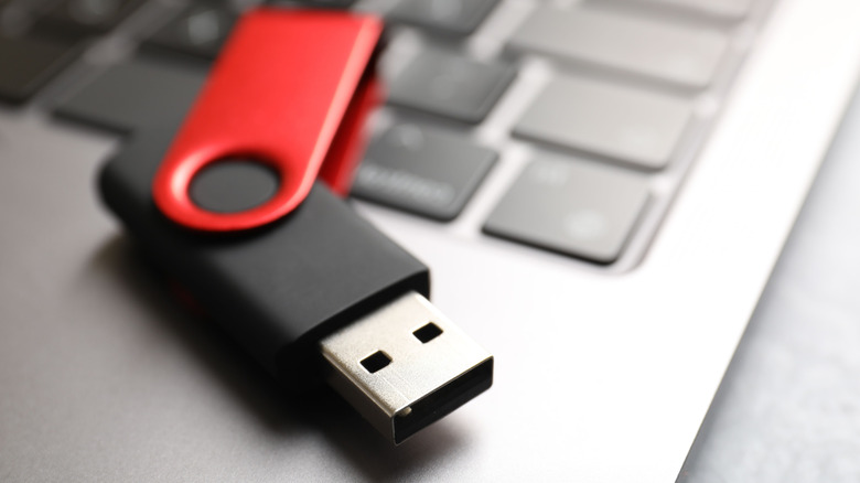 Modern flash drive resting atop a laptop keyboard.