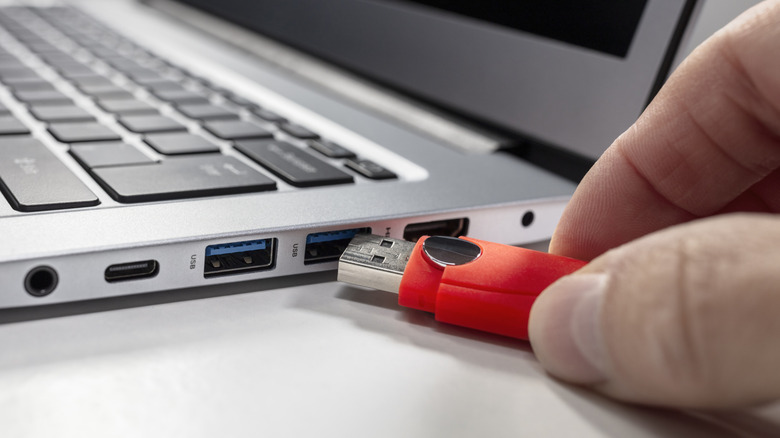 A person connecting a USB flash drive to a laptop