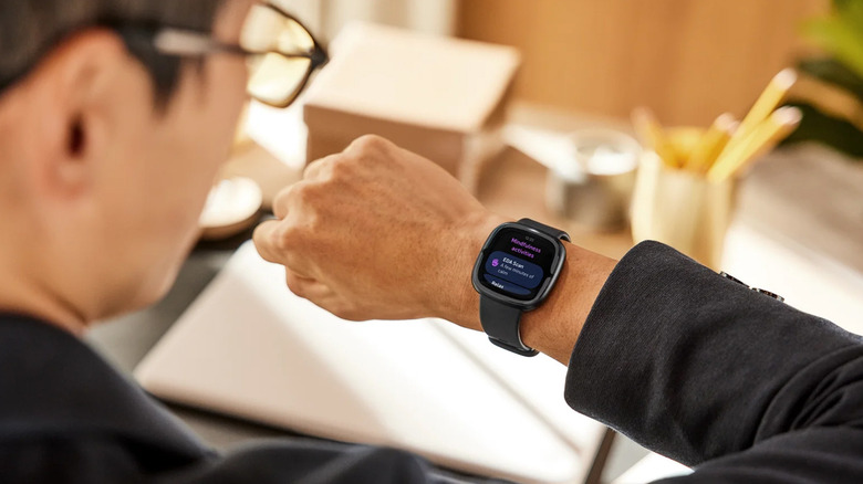 A man looking down at the Fitbit Sense 2 on his wrist
