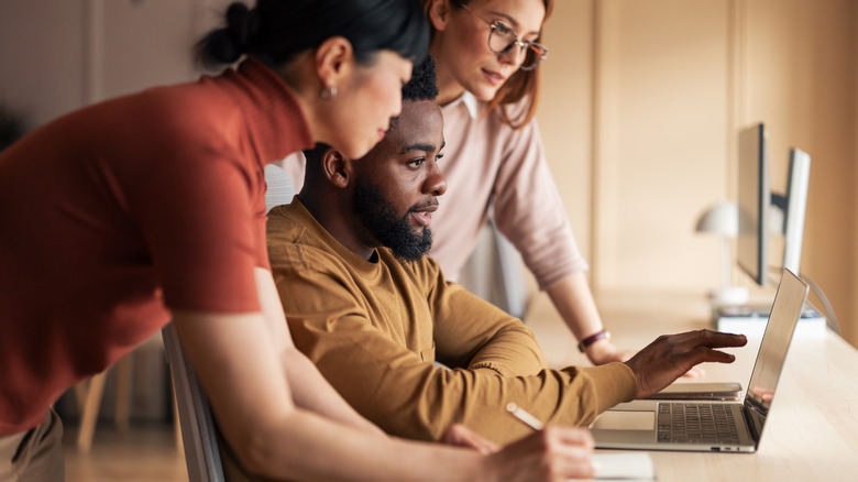 Team of three workers looking at computer together