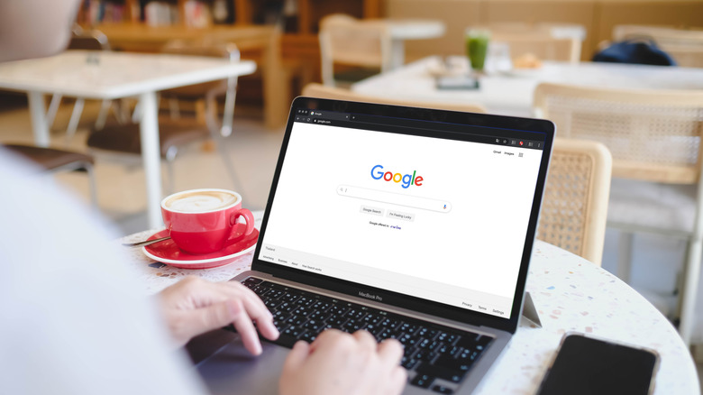 Person using computer which displays the Google home screen.