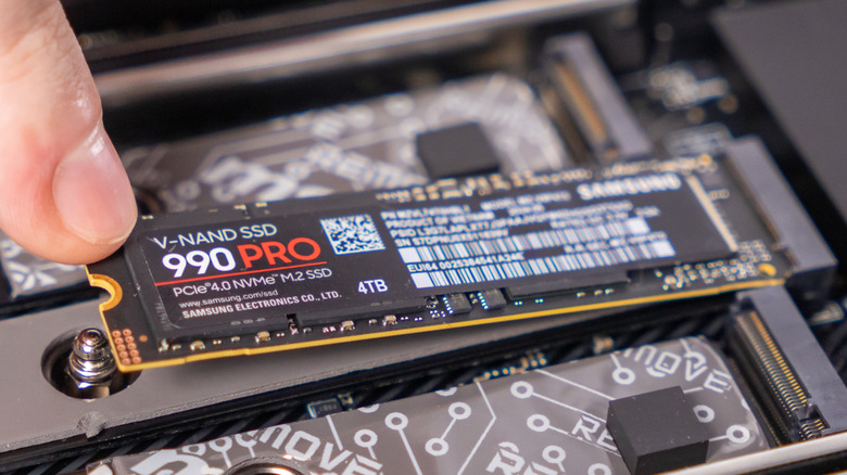 A person installing SAMSUNG 4TB M.2 PCIe Gen4 NVMe 990 PRO SSD on a motherboard