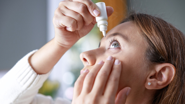 A woman putting eye drops in her eyes