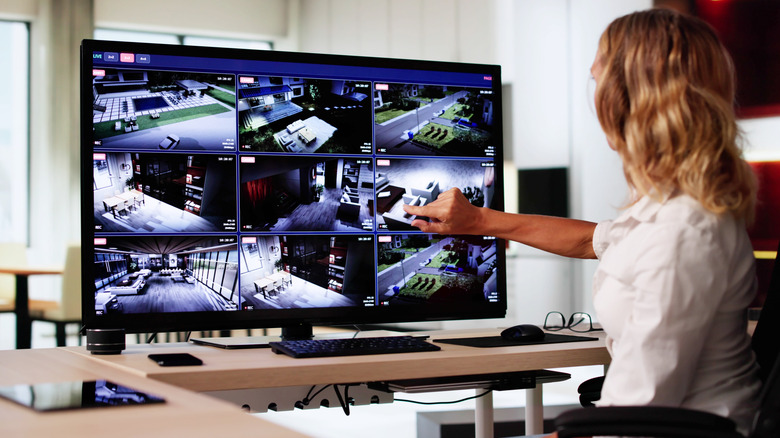 Woman at desk monitoring home security camera footage