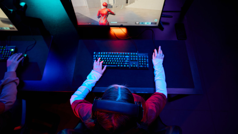 An overhead shot of a gamer wearing headphones and playing a computer game