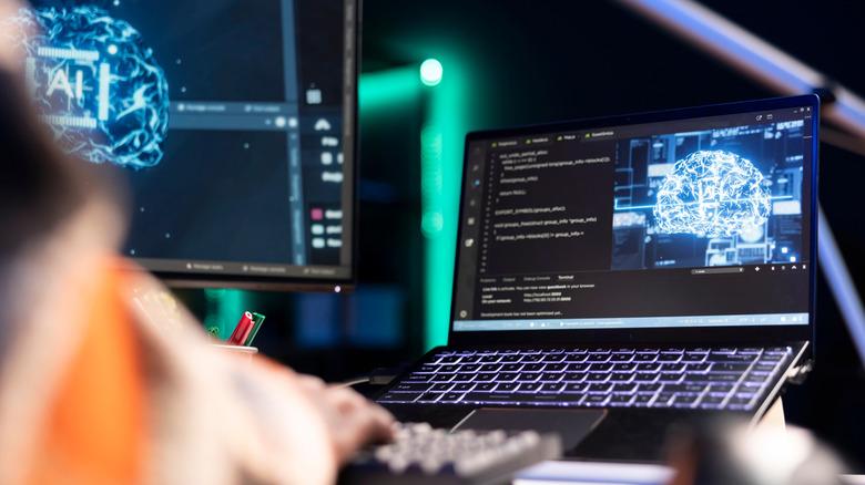 A person working on a laptop with a monitor in the background