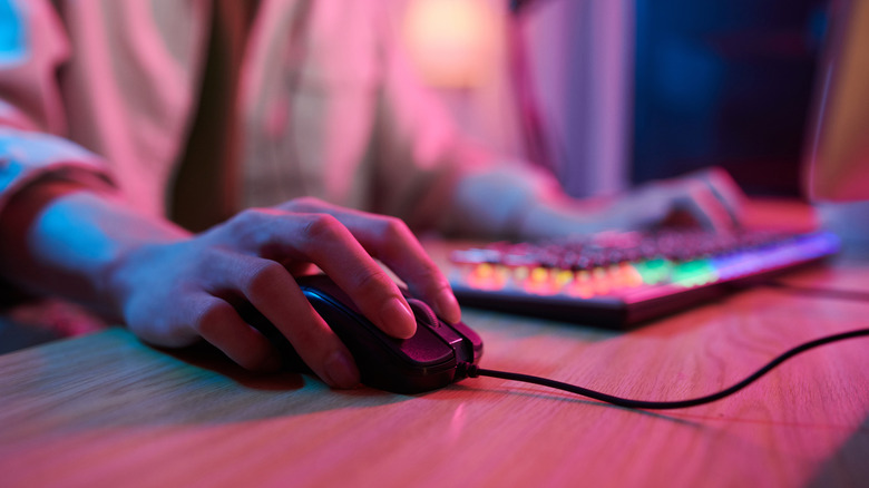 Hand holding mouse with fingers on both buttons