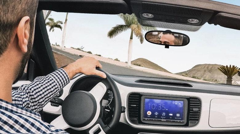 A man driving with the Sony XAV-AX3200 media receiver installed on the dashboard