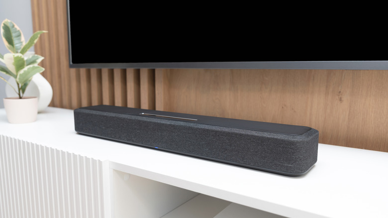 A soundbar placed on a unit under a TV screen