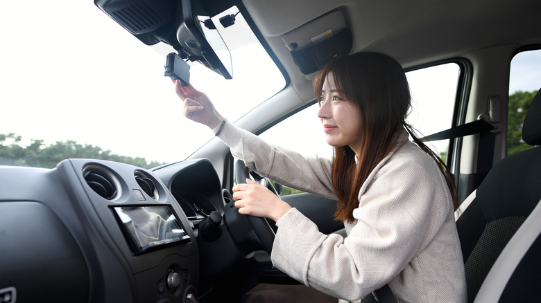 A woman setting up her dashcam in her car