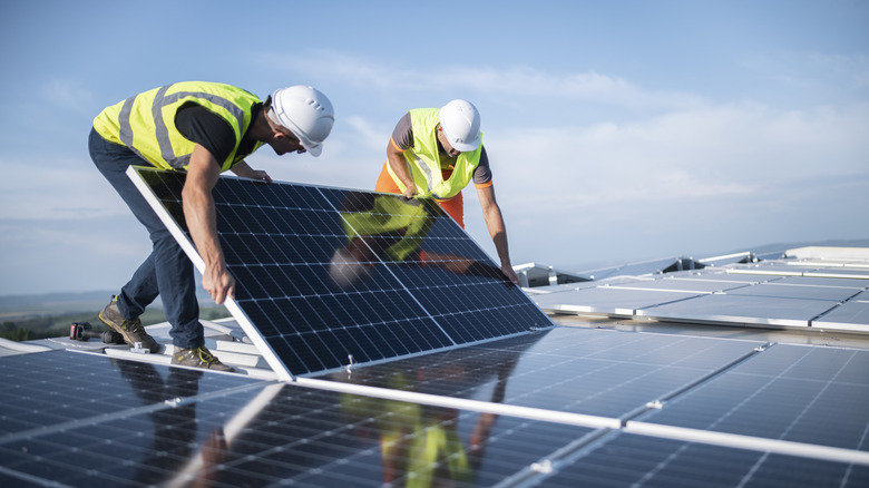 Engineers installing a large two panel solar panel on a roof.