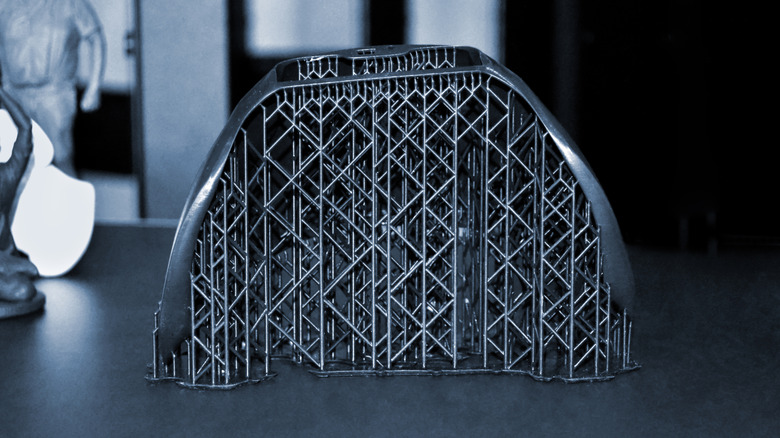 3D printed model with dense support structures still attached.