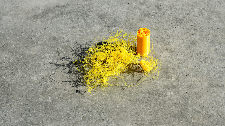 Failed 3D print with tangled yellow filament beside a partially printed object.
