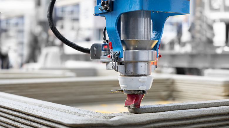 A large construction 3D printer nozzle pouring concrete layers