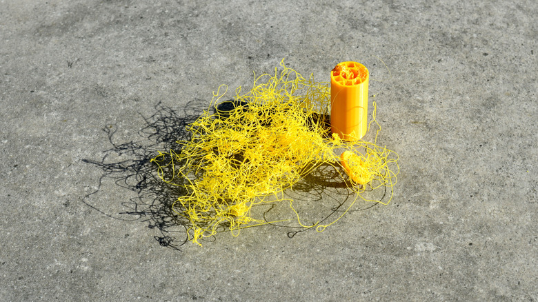 Failed 3D print with tangled yellow filament beside a partially printed object.