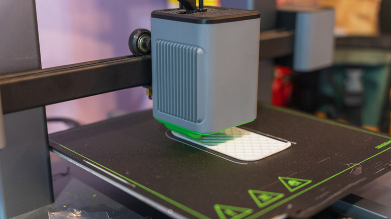 Desktop 3D printer laying down filament on a build plate.