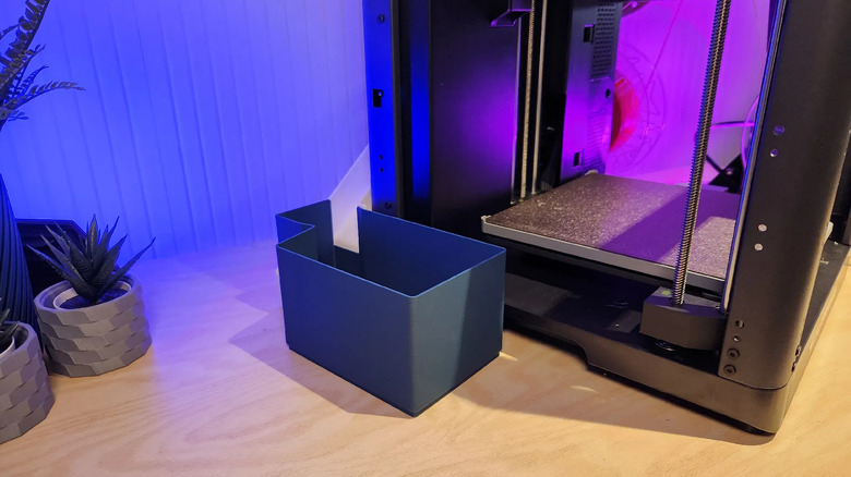 FlashForge AD5X poop purge chute directing filament waste into a bucket beside the 3D printer.