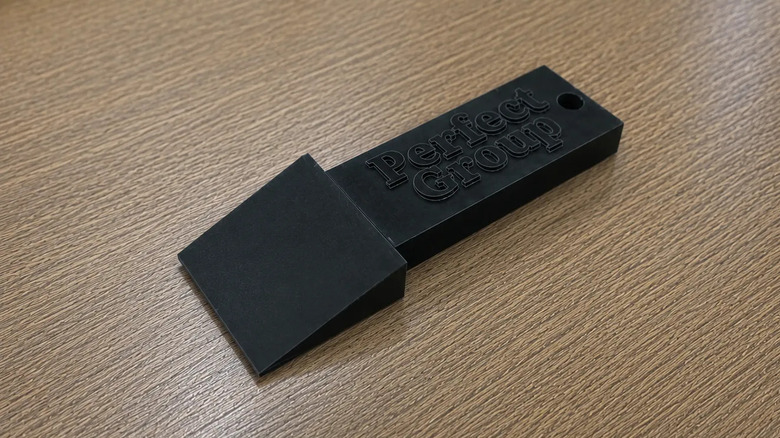 Black 3D printed bed scraper on a wooden table.