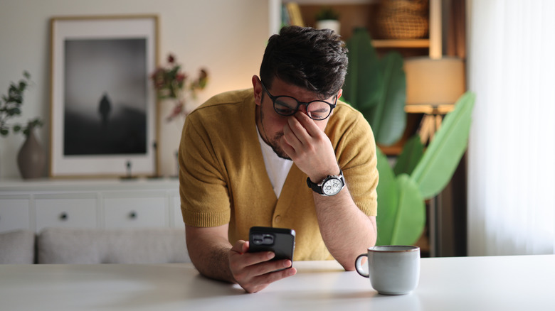 Person looking stressed while checking a smartphone